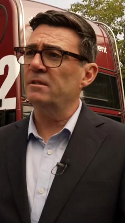 Andy Burnham stood by a bus