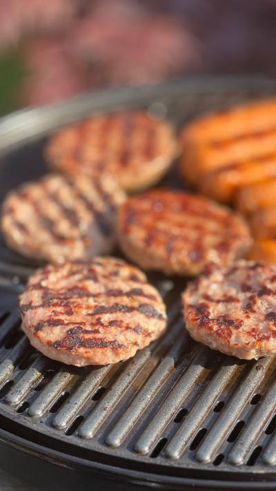 Beef burgers and sausages cooking on a home BBQ
