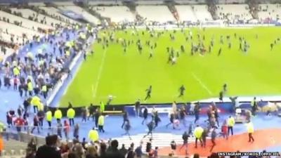 Amateur footage of people streaming across pitch