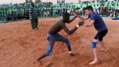 BBC reporter Ben Zand (R) and his opponent (L) in a wrestling match in Khartoum