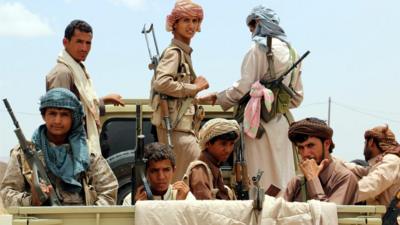 Yemeni fighters ride on a vehicle during an offensive against Houthi rebels positions