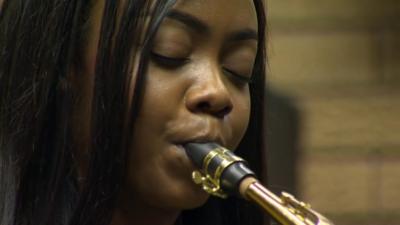 Suzy Eises plays a saxophone