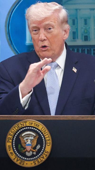 Trump gestures with his right hand while facing reporters at the White House.