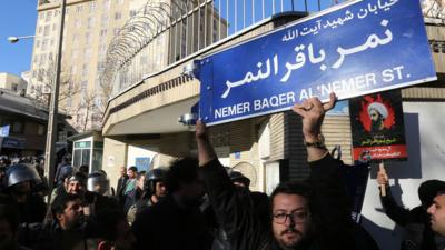 An Iranian holds a street sign bearing the name of Shia cleric Nimr al-Nimr during a demonstration against his execution by Saudi authorities