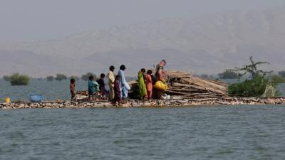 People stand on a mound, surrounded by flood waters