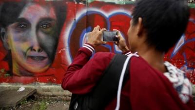 Young man takes picture of mural