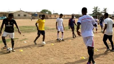 Young Nigerian footballers doing a drill on a training pitch