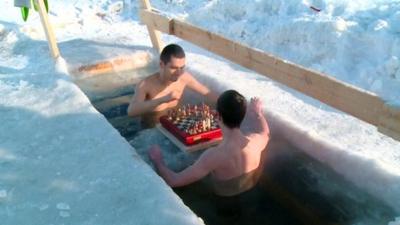 Two contestants play chess in a freezing pool.