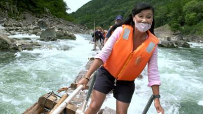 Carmen Roberts rides on a log raft down a river