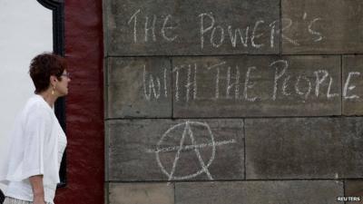 A woman walking past a message drawn in chalk during an anti-fracking demo which says: "The Power's with the People!"