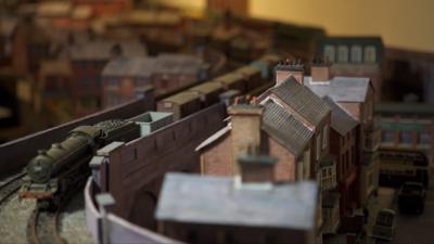 Model railway train next to a row of houses