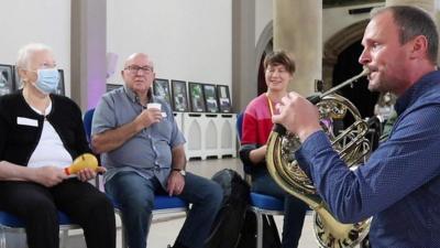 Man playing french horn in music class