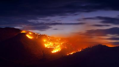 Wildfire burning in a valley at sunset