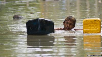 A flood-affected resident swims through floodwaters