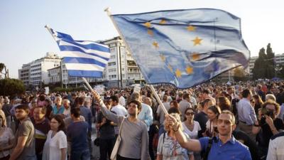 Demonstrators waving Greek and EU flags
