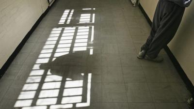 Teenager stands at prison window