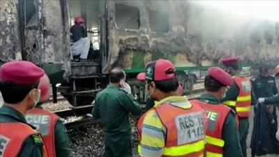 Emergency authorities survey the wreckage of a train fire in Pakistan