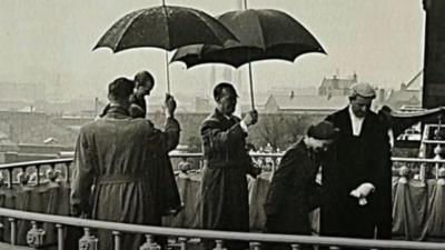 Men holding umbrella's for the Queen