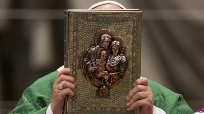 Pope Francis holds the Gospel book