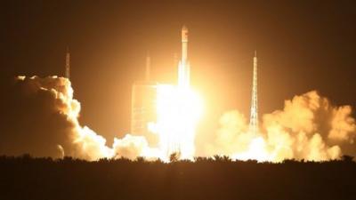 Spectators watch as a Long March 7 (CZ-7) rocket lifts off the launch pad in Wenchang in southern China"s Hainan Province