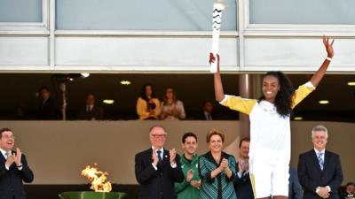 Brazilian volleyball player Fabiana Claudino holds the Olympic torch after receiving it from Brazilian President Dilma Rousseff