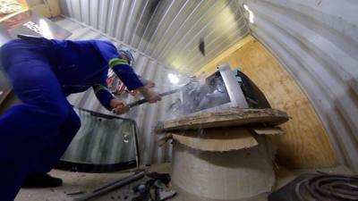 A man smashing a TV with a sledgehammer