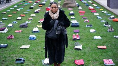 Yemi Hughes holding clothes her son Andre was wearing when he was stabbed to death