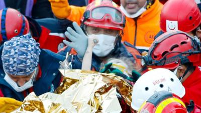 Girl clinging to rescue worker's thumb