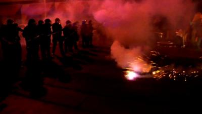 Police stand in a line amid cloud of smoke