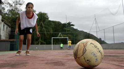 A girl about to kick a football