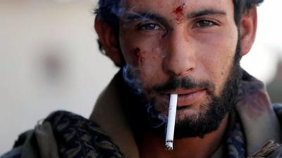 A member of the Syrian Defence Forces smokes a cigarette