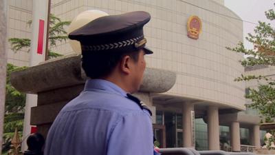 Police officer guarding the entrance to the Tiajin court.