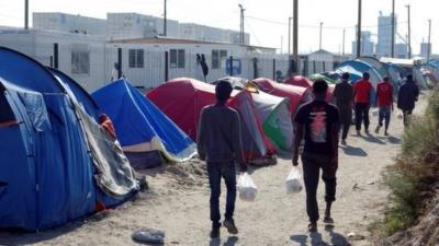 Migrants walk in the northern area of the camp called the "Jungle" in Calais,