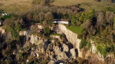 A house sits above a large landslip