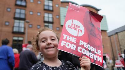 Child holds a Jeremy Corbyn placard