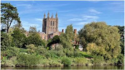 Blue sky behind a church with a river in the foreground