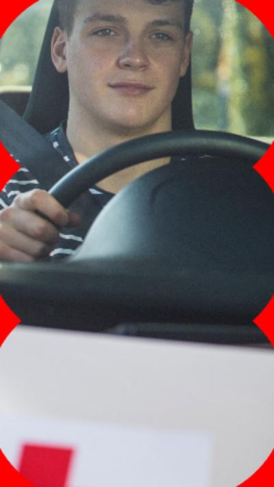 Young man driving a silver car with a red Learner badge on the front