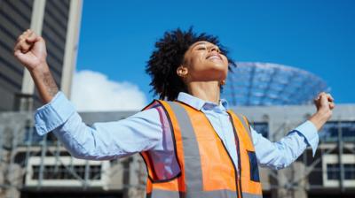 A woman wearing a blue shirt and orange bib with her arms outstretched