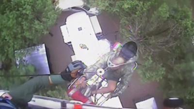 A person being rescue by a winch from a helicopter