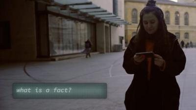 BBC journalist walking into building looking at smartphone