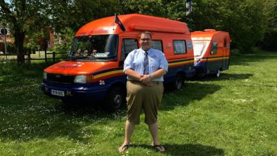 Jared Colclough stands in front of the camper and caravan he's converted to look like lifeboats