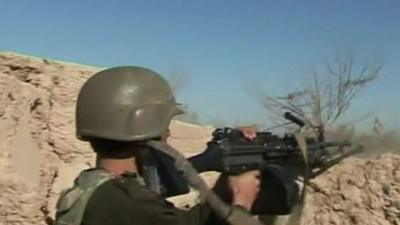 A soldier firing over a wall