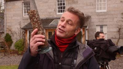 Chris Packham from Winterwatch holding a bird feeder.