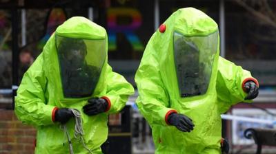 Two emergency service workers in bright green hazmat suits