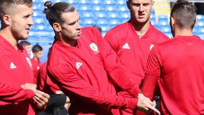 Gareth Bale plays a mock golf shot in Wales training
