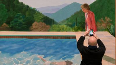 Man takes photograph of Hockney work