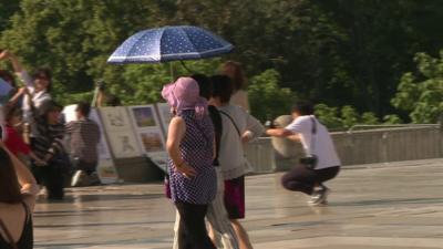 Three women shelter under an umbrella during a heatwave in Paris