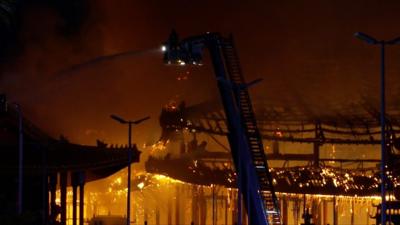 Firefighter hosing temple fire from a crane