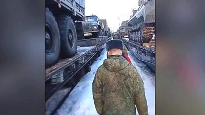 A soldier walks alongside Russian military vehicles on rail tracks