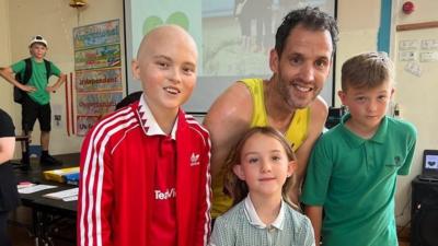 Dan smiles after completing his treadmill challenge with 12-year-old Harley and his family in the picture